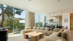 A modern living room with a large sectional sofa, a coffee table, and a dining area with a table and chairs.