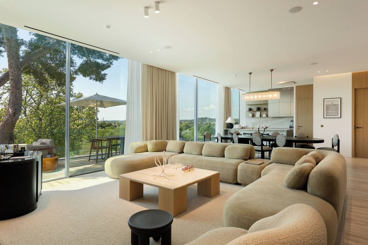 Een moderne woonkamer met een grote hoekbank, een salontafel en een eetgedeelte met een tafel en stoelen.