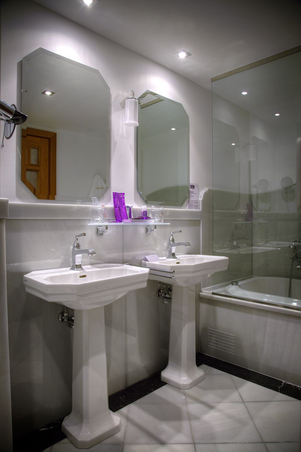Een badkamer met twee wasbakken, een spiegel en een bad.