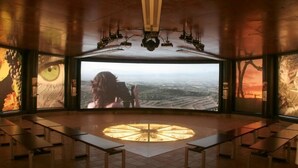Un espacio amplio con una gran pantalla panorámica, varias luces de techo y una lámpara circular en el suelo.