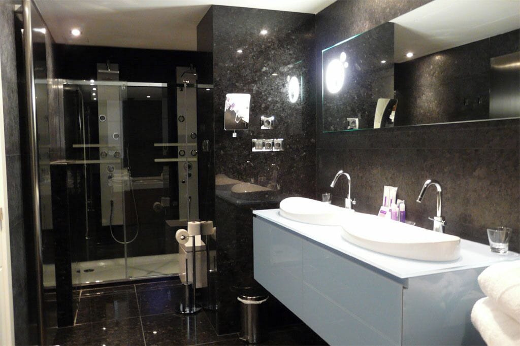 A modern bathroom with a glass-enclosed shower, a double sink vanity, and a large mirror.