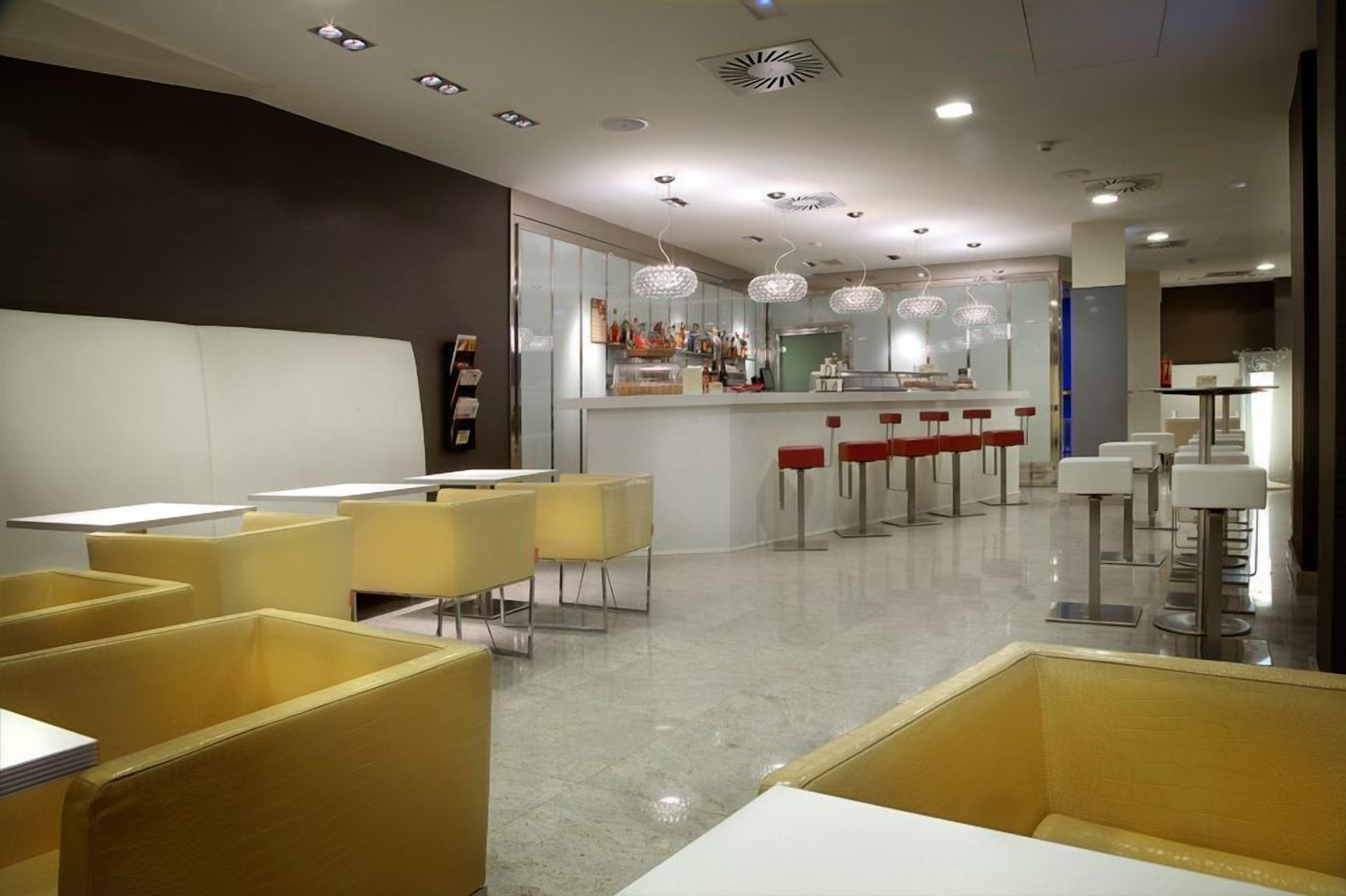A modern restaurant with yellow booths, a bar area, and pendant lighting.
