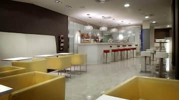 Restaurante moderno com assentos em amarelo, área de bar e iluminação pendente.