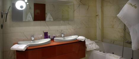 A bathroom with two sinks, a mirror, and a bathtub.