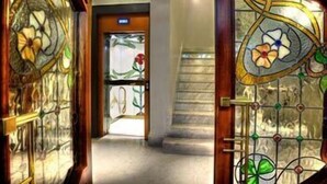 Un pasillo con una puerta de madera que tiene un vitral con diseños florales.