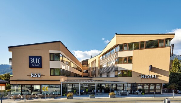 A modern hotel with a bar, outdoor seating, and a mountain view. - TUI BLUE Schladming (Schladming)