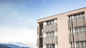 Ein modernes Gebäude mit flachem Dach, großen Fenstern und einem Balkon mit Metallgeländern.