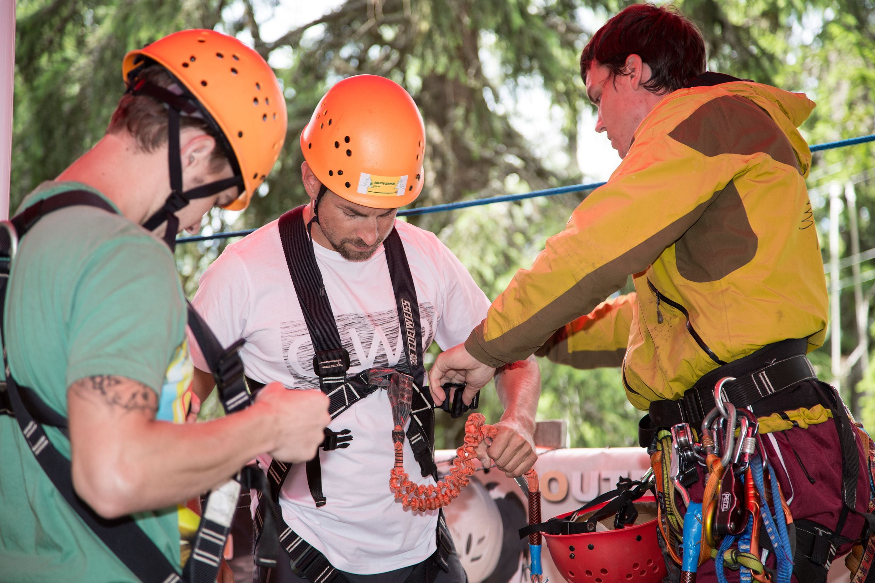 A group of people preparing for an activity, with safety helmets and harnesses visible.