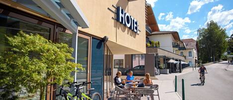 A hotel with outdoor seating and a bicycle parked outside.