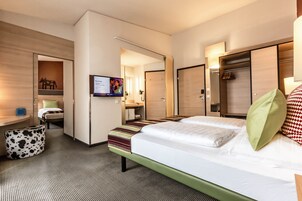 Una habitación de hotel con cama, escritorio, televisor, armario y baño.