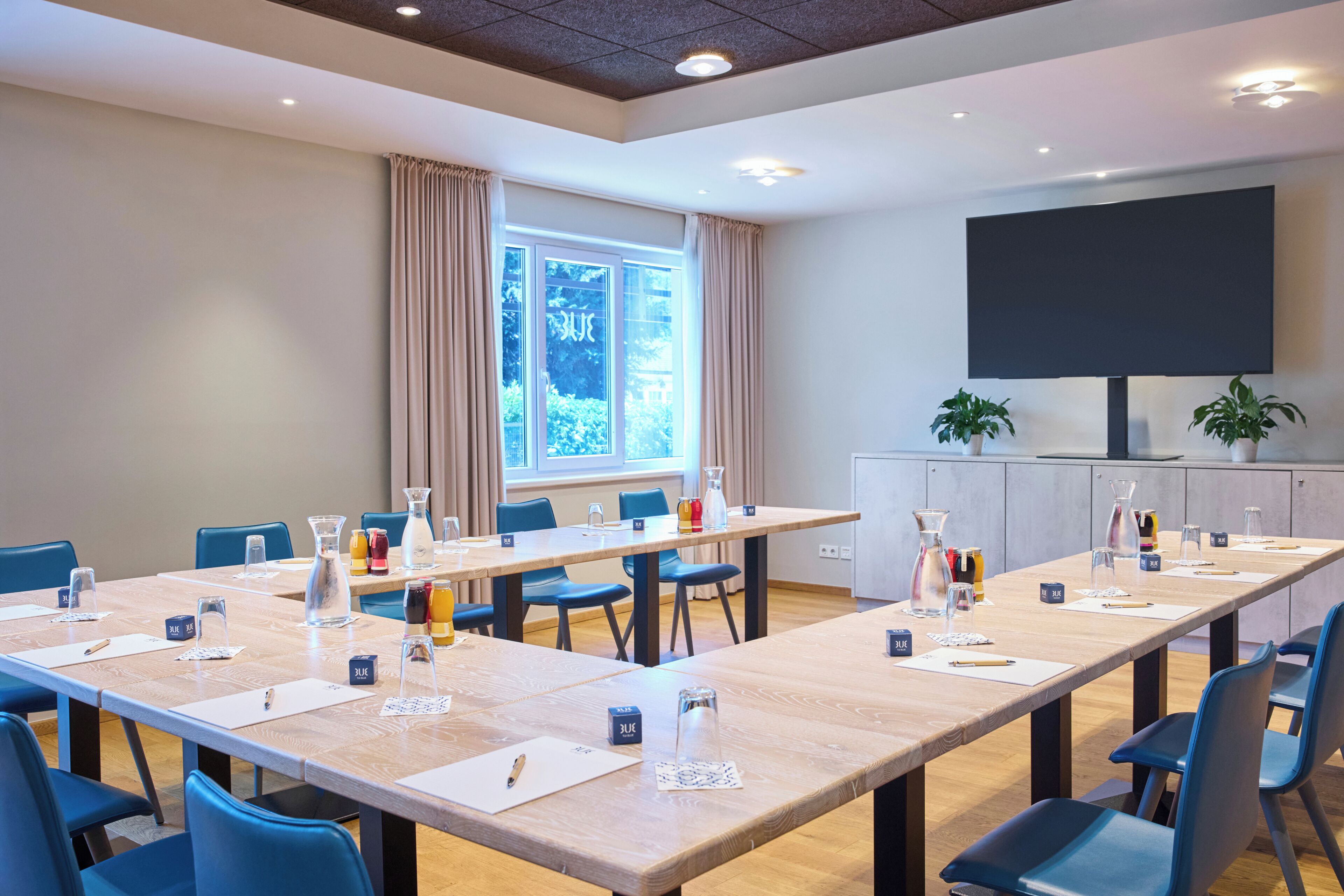 A conference room with a long table, chairs, nameplates, and a projector screen.