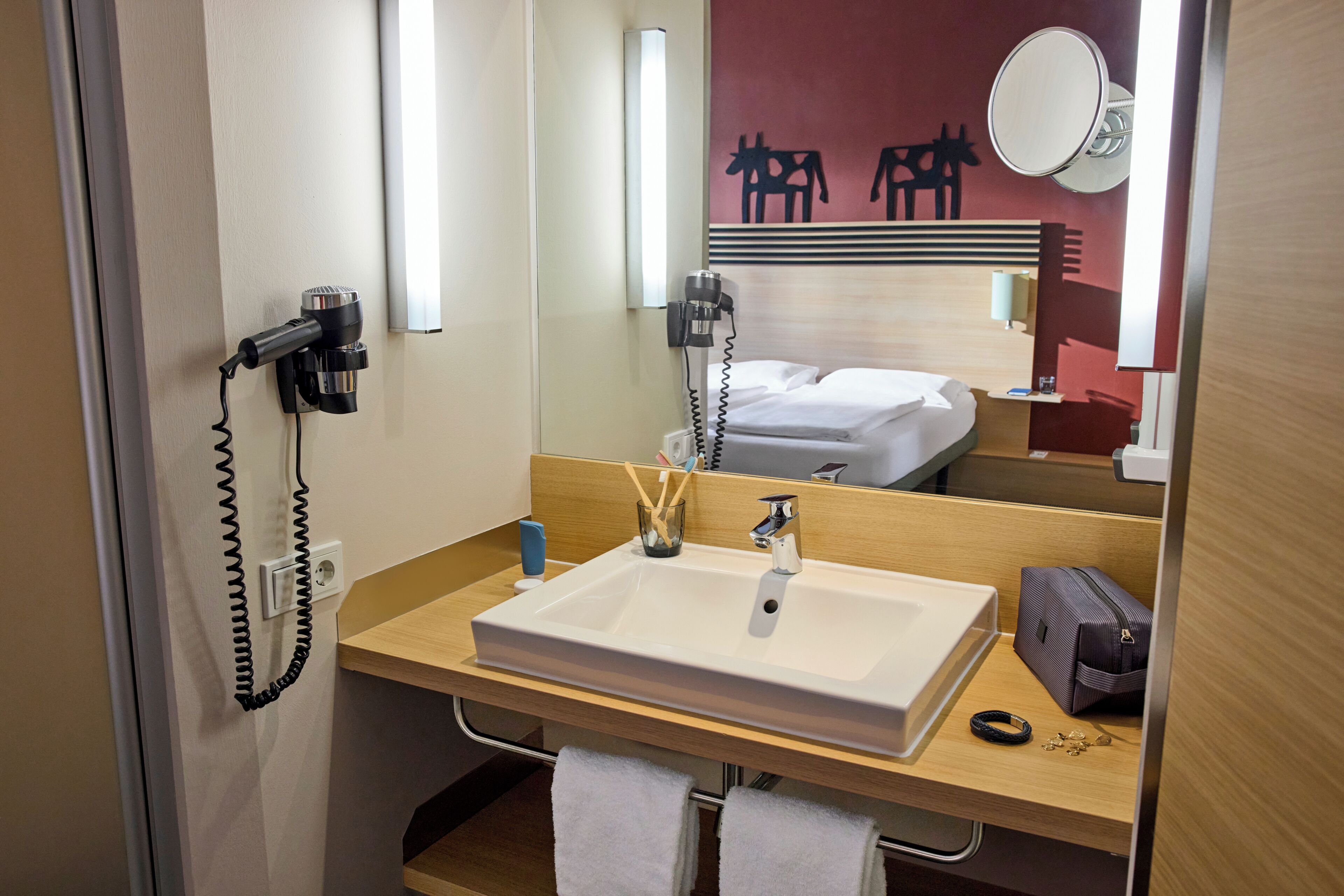Un baño de hotel con lavamanos, espejo y perchero para toallas.