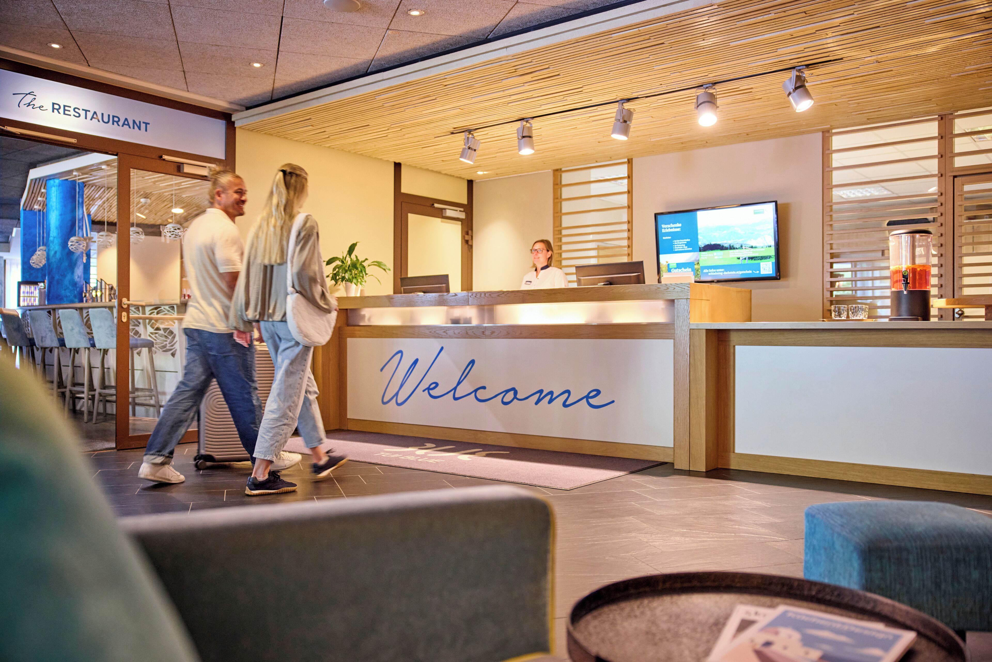 A reception area with a 'Welcome' sign, a reception desk, a television, and a coffee machine.