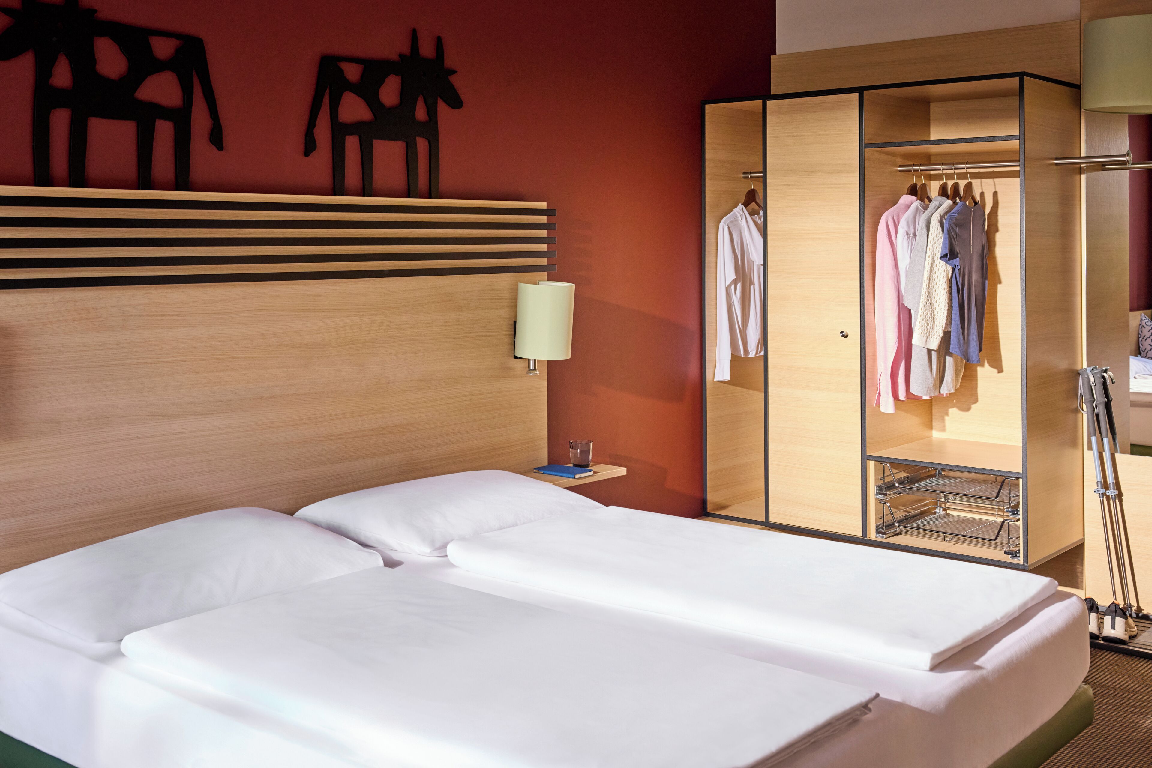 A hotel room with a bed, a wardrobe, and a mirror.