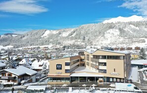 A hotel with a bar and restaurant, surrounded by snow-covered buildings and mountains. - TUI BLUE Schladming (Schladming)