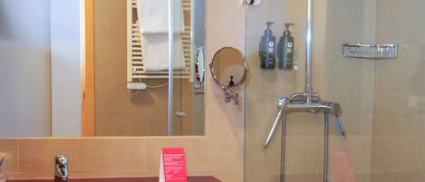 Un baño con ducha de vidrio, un lavamanos rojo y un espejo.