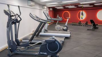 Un gimnasio con diferentes equipos de ejercicio, incluyendo cintas de correr, elípticas y mancuernas.
