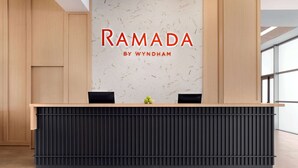 Un mostrador de recepción con detalles de madera y un diseño de panel negro. Sobre el mostrador, una pared con el texto 