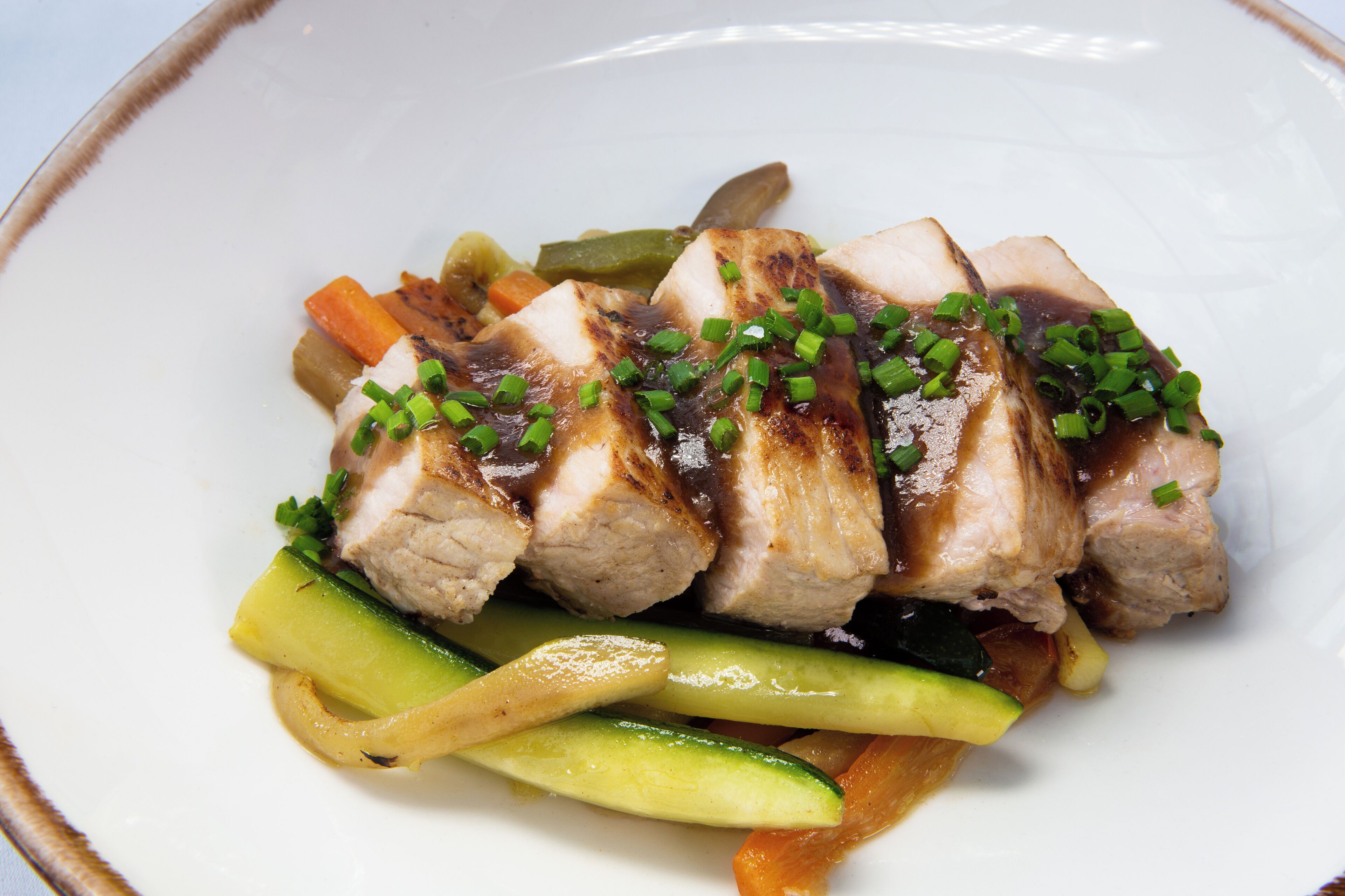 A plate of sliced meat with vegetables and green onions.