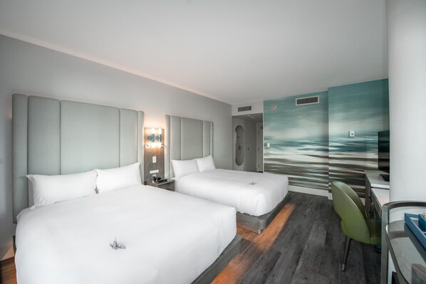 A hotel room with two beds, a desk, a chair, a shower, and a mural on the wall. - Coast Coal Harbour Vancouver Hotel by APA (Vancouver)