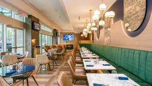 A restaurant with a long counter, booths, and a TV screen.
