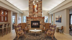 A spacious living area with a stone fireplace, leather armchairs, and a dining area with a bar. - Residence Inn by Marriott Gravenhurst Muskoka Wharf (Gravenhurst)