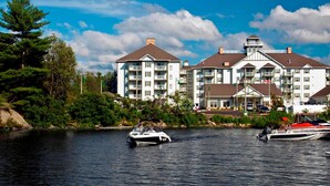 A waterfront hotel with multiple balconies, a dock, and a boat. - Residence Inn by Marriott Gravenhurst Muskoka Wharf (Gravenhurst)