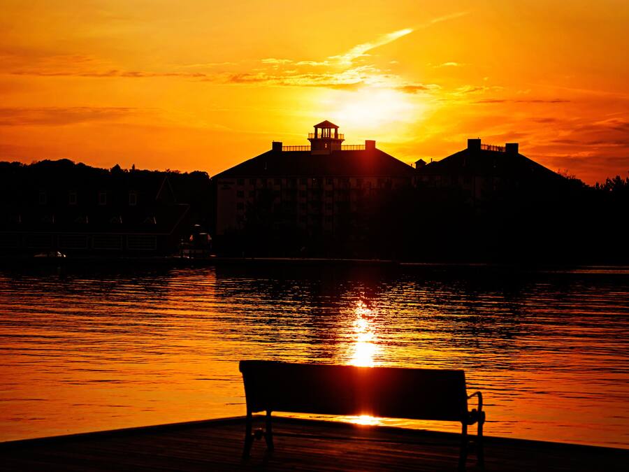 A sunset over a body of water with a bench in the foreground.