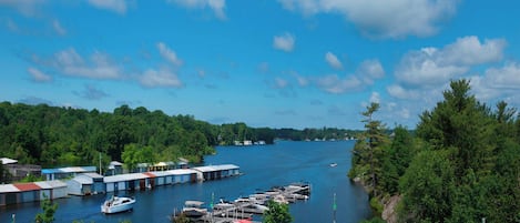A marina with boats docked, a parking area, and a small building.