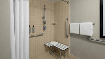 Un baño con ducha, barras de apoyo, un banco y un perchero para toallas.