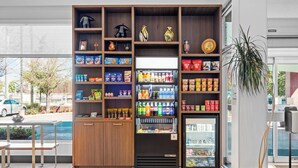 Máquina expendedora con aperitivos y bebidas, un expositor refrigerado y un estante de madera con diversos artículos.