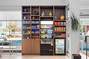 Ein Getränkeautomat mit Snacks und Getränken, eine gekühlte Warenpräsentation und ein Holzregal mit verschiedenen Artikeln.