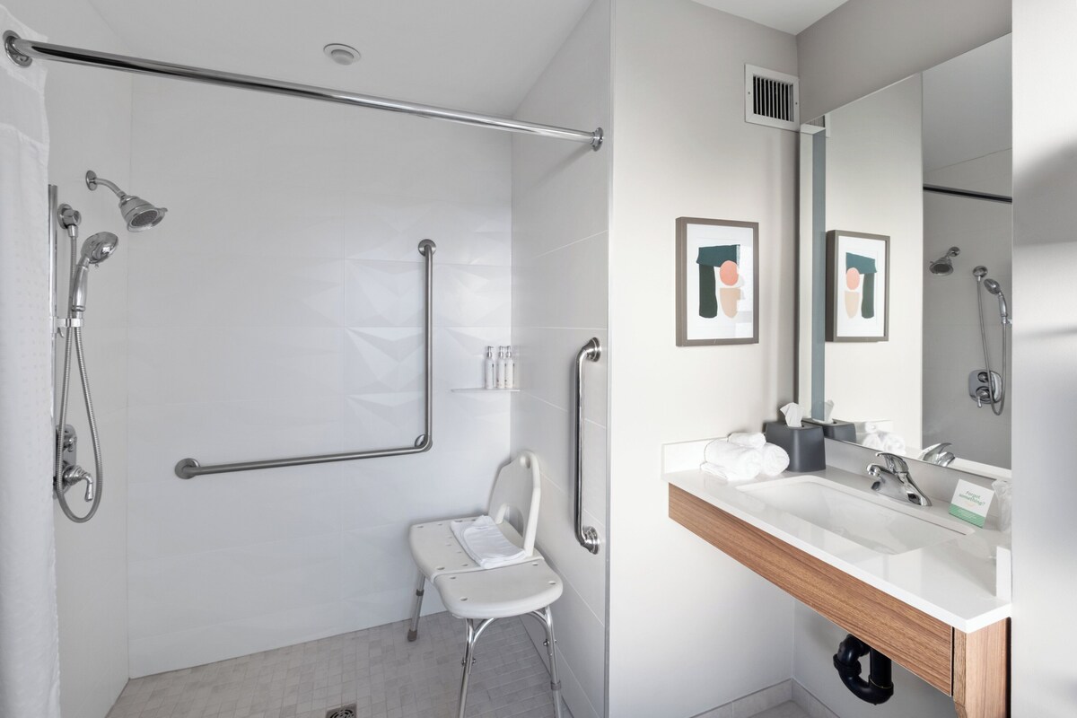 A modern bathroom with a shower, a toilet, and a sink with a mirror.