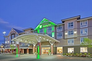 Un hotel Holiday Inn con ingresso coperto, diversi piani e una facciata ben illuminata.