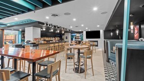 Un área de bar moderna con diversas opciones de asientos, incluyendo taburetes y mesas redondas.