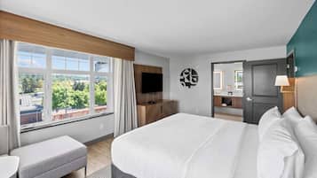 A hotel room with a large bed, a TV, a desk, and a bathroom visible through an open door.