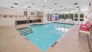 Una piscina interior con carriles delimitados, un cartel de prohibido bucear y una silla para salvavidas.