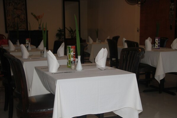 A restaurant with tables set for dining, featuring white tablecloths and neatly arranged napkins. - Seminyak Paradiso Hotel (Seminyak)