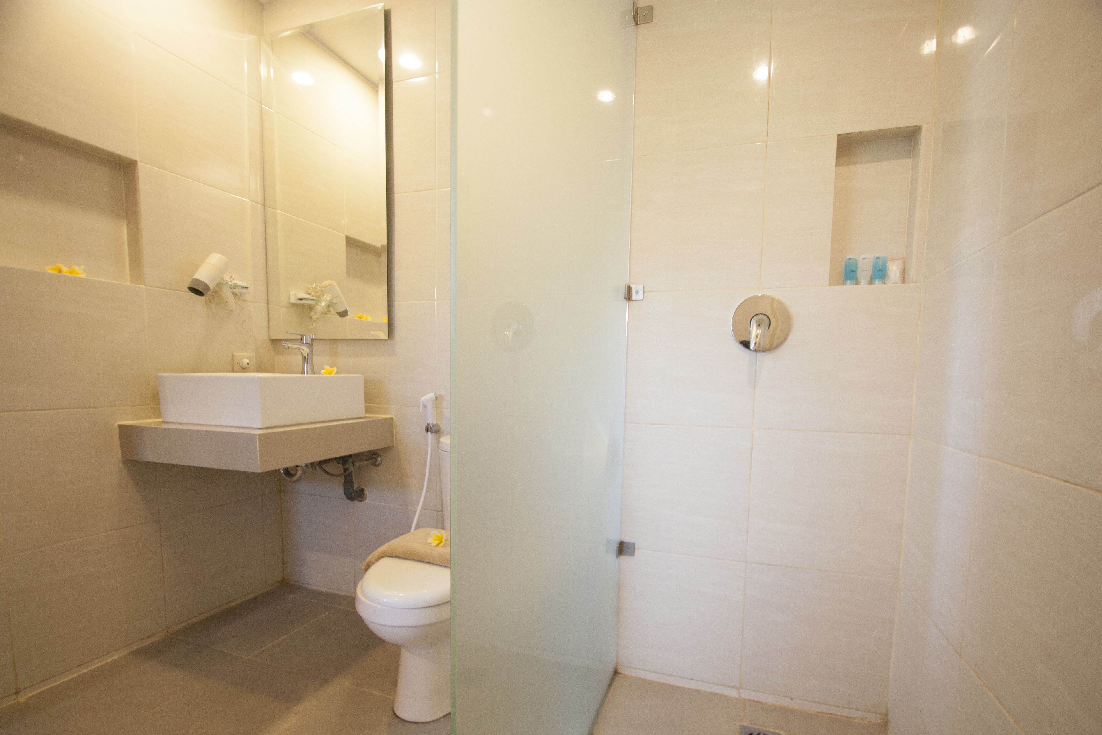 Une salle de bain moderne équipée d’un lavabo, de toilettes et d’une zone douche.