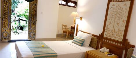 Quarto de hotel com duas camas, uma escrivaninha, uma cadeira, um abajur e um telefone.