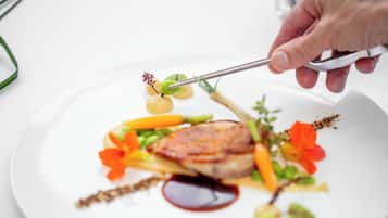 Una persona usando unas pinzas para colocar comida en un plato.