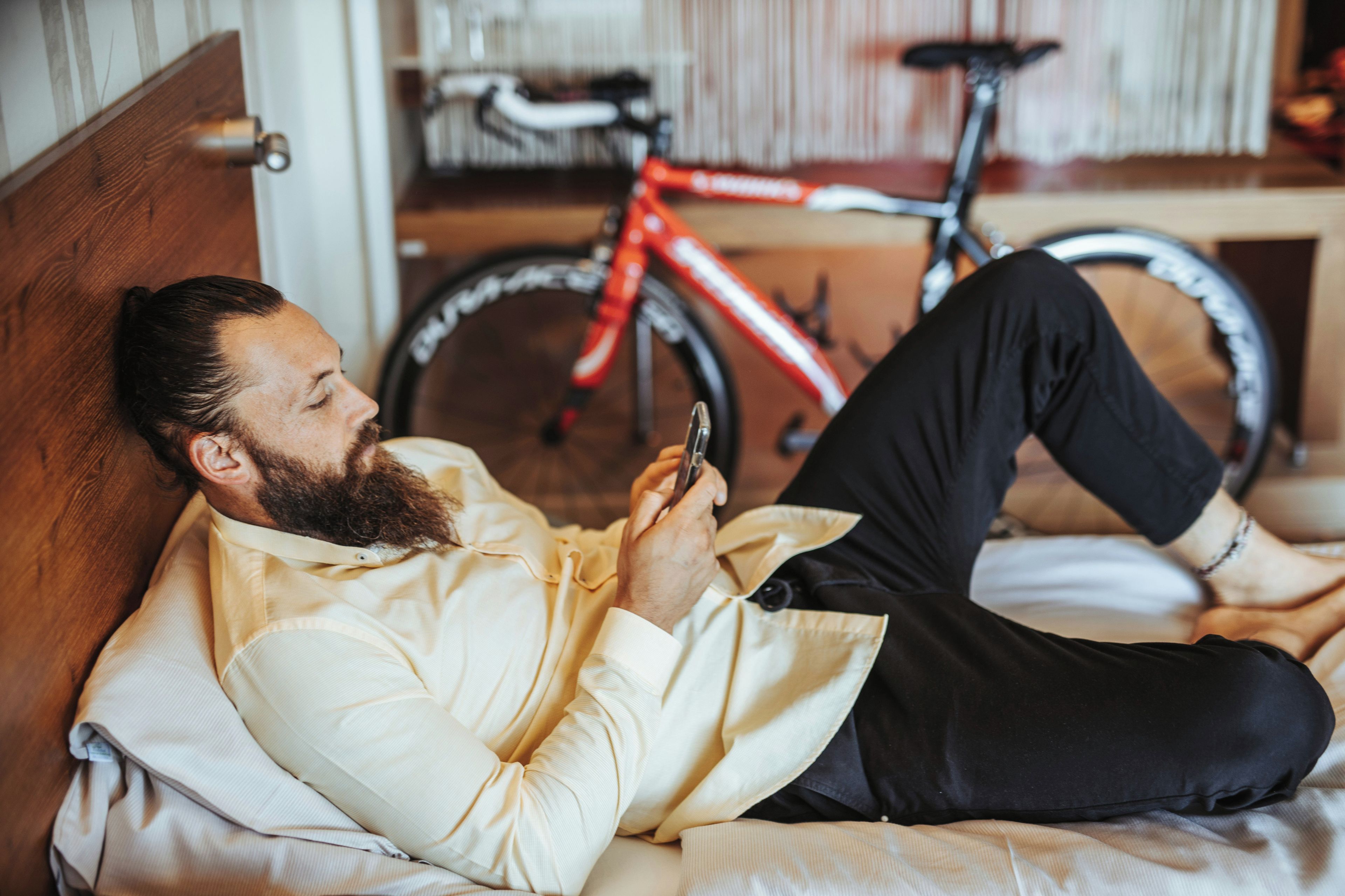 A person lying on a bed with a bicycle in the background.