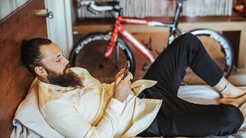 A person lying on a bed with a bicycle in the background.