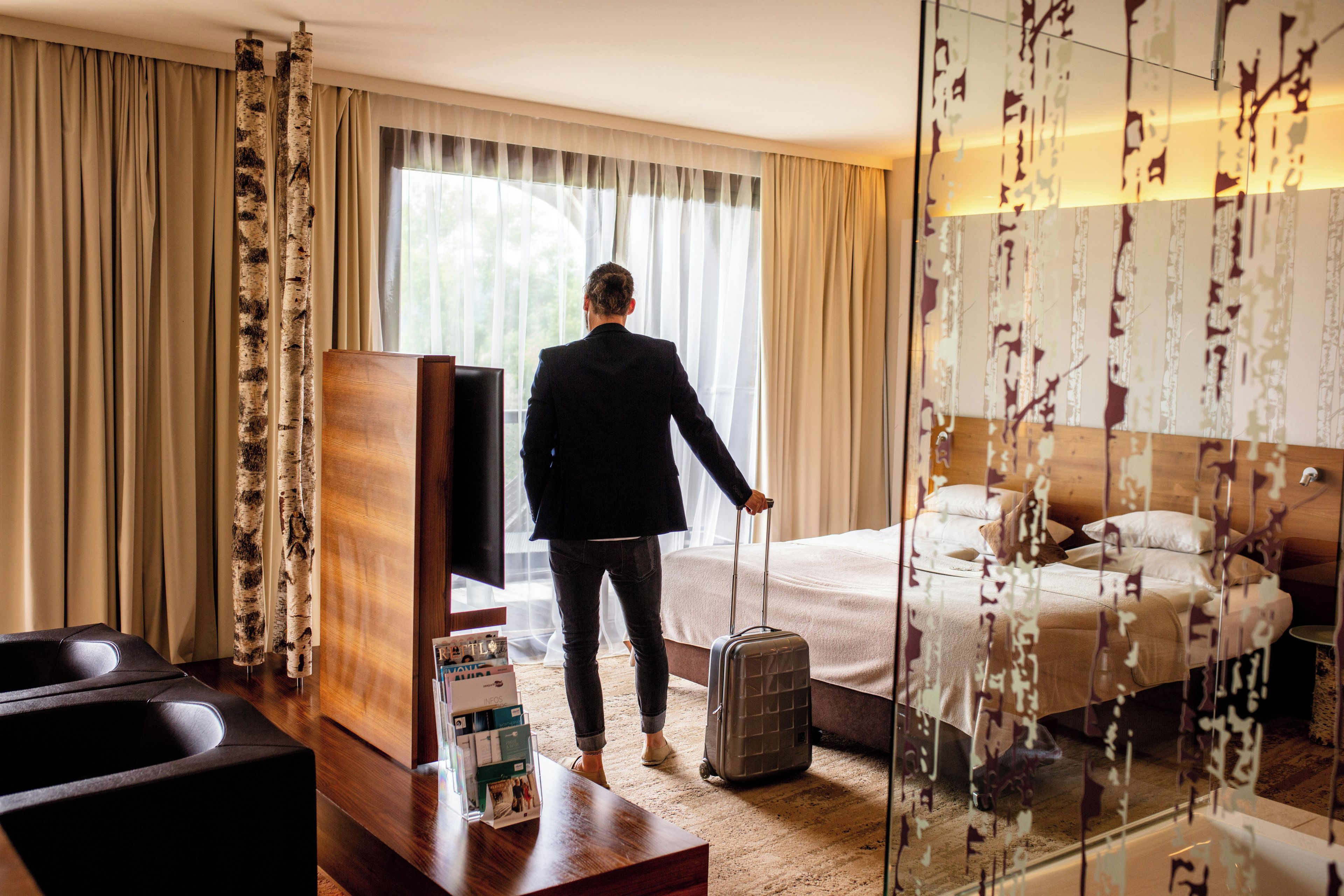 Een hotelkamer met een bed, een televisie, een bureau en een koffer.