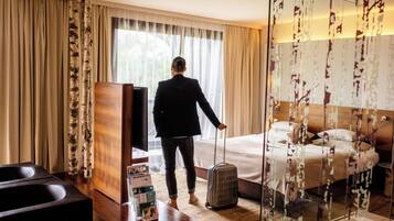Een hotelkamer met een bed, een televisie, een bureau en een koffer.