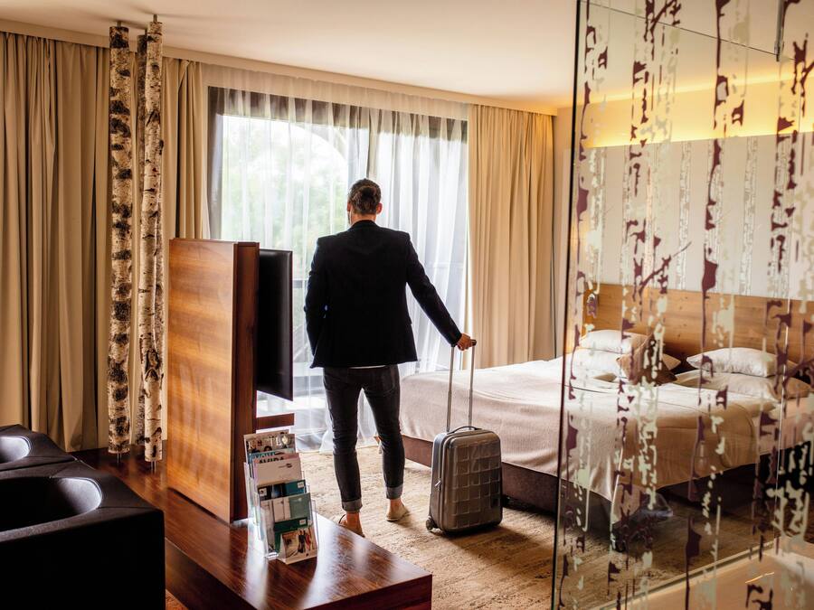 A hotel room with a bed, a TV, a desk, and a suitcase.