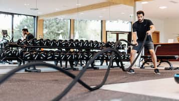 Un gimnasio con equipamiento de ejercicio y una persona usando una máquina de remo.