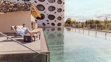 Un espace aménagé au bord de la piscine, avec deux chaises longues et une personne allongée sur l’une d’elles.