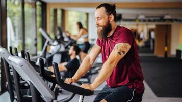 A gym with stationary bikes and a person using one.