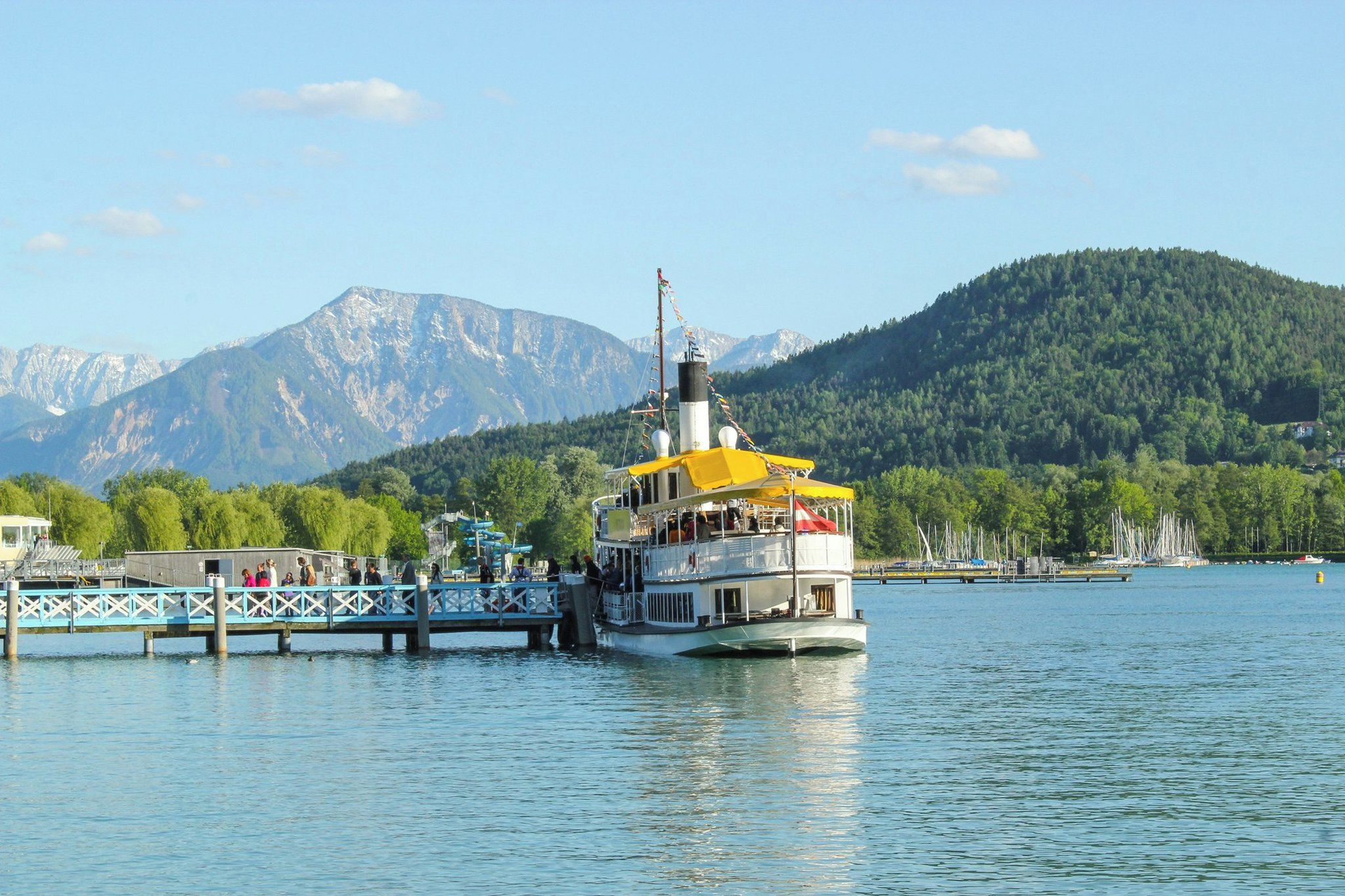 Ein Boot liegt an einer Pier vor einer Bergkulisse.